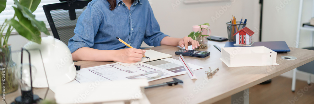 Fototapeta premium Architect Workspace Asian Women Design House Plans Project with Blueprints Asian Women Real Estate and Calculator for Build Cost