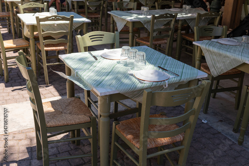 Outdoor Taverna Table Setting. Traditional Greek taverna table set with plates and glassware, shaded and ready for guests in Zakynthos, Greece.
