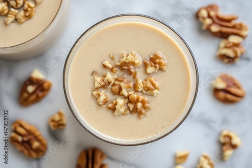 Creamy nut-based smoothie topped with chopped walnuts on a marble countertop, inviting and fresh