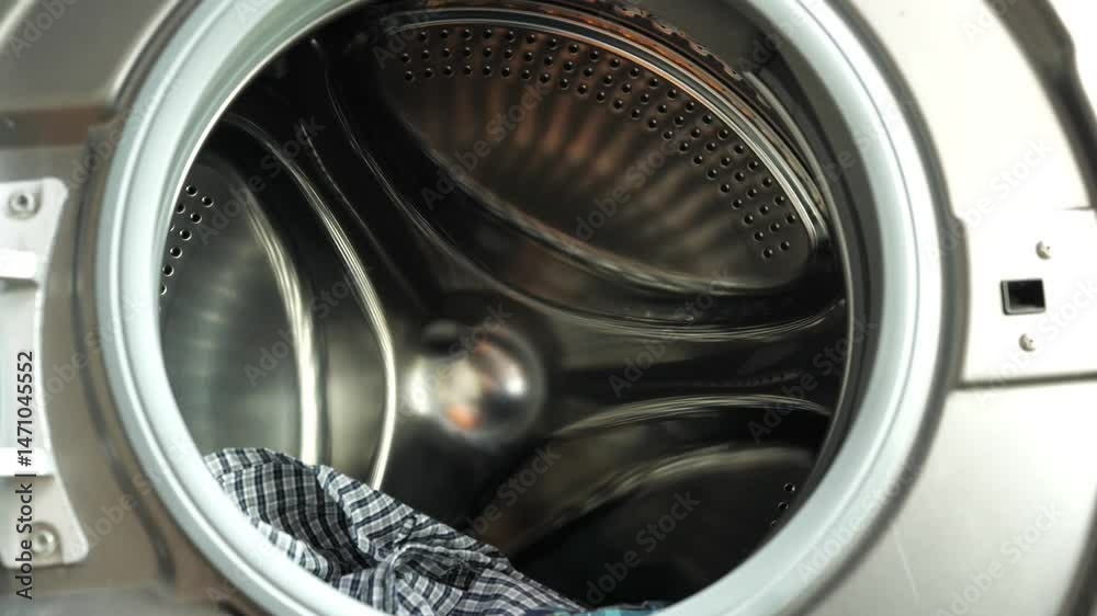 A slow-motion shot of clothes being tossed into the washing machine to prepare for cleaning, depicting the concept of washing clothes. A slow-motion shot of clothes being tossed into the washing machine to prepare for cleaning, depicting the concept of washing clothes.