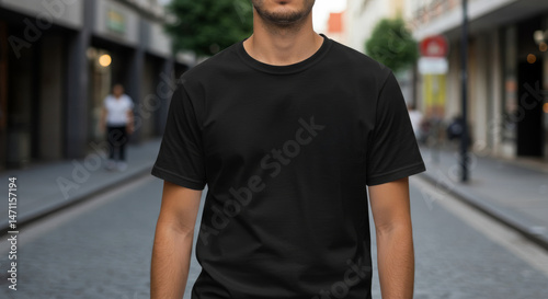 Close-up of a man in a basic black tee shirt template against a blurred cityscape