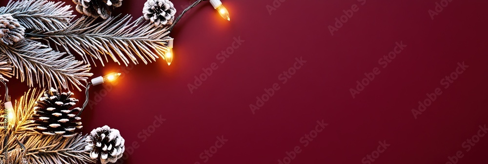 Obraz premium photo of silver christmas string lights with tree branches and pine cones isolated on solid burgundy background