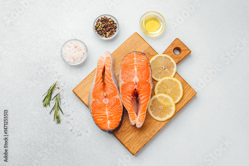 Fresh salmon fillets on a cutting board with herbs and lemon slices