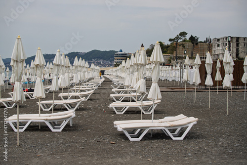 Fototapeta Naklejka Na Ścianę i Meble -  A beach with many white umbrellas and white lounge chairs