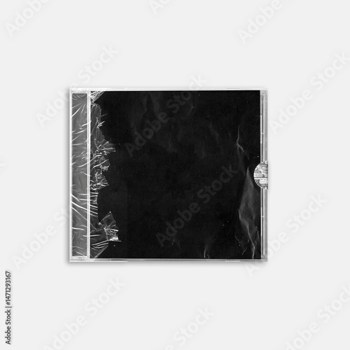 Close-up of a CD case wrapped in torn transparent plastic with a black background insert. Ideal for album artwork mockups, grunge designs, or retro music packaging.