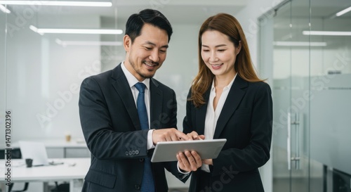 Smiling Asian Business Colleagues Reviewing Tablet Data