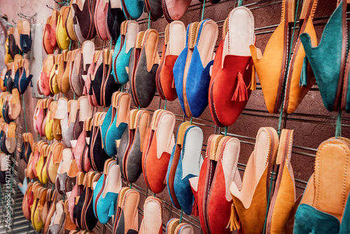 Traditional Moroccan leather slippers in vibrant colors displayed on a metal rack, showcasing the craftsmanship of local artisans