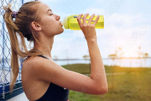 Woman drinking water at workout outdoors