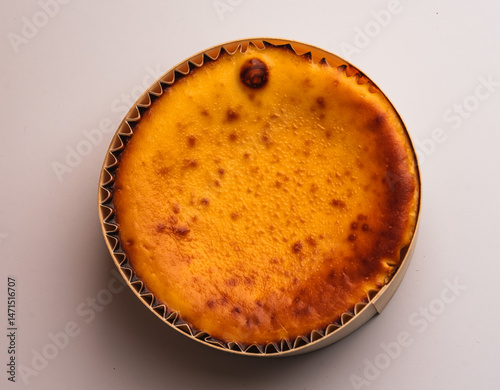 Golden Brown Baked Cheesecake in a Wooden Mould Against Neutral Background
