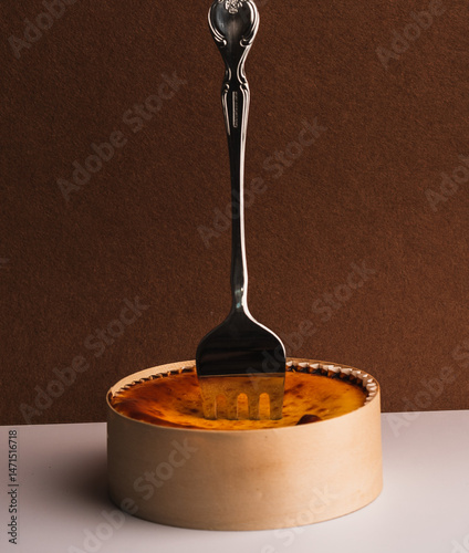 Gourmet Cheesecake with Fork on Wooden Base and Brown Backdrop