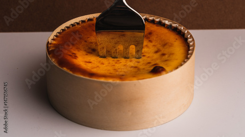 Custard Tart with Fork in Wooden Mold on White and Beige Background