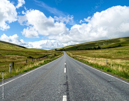 Serene Open Road Through Lush Green Hills Under Blue Sky