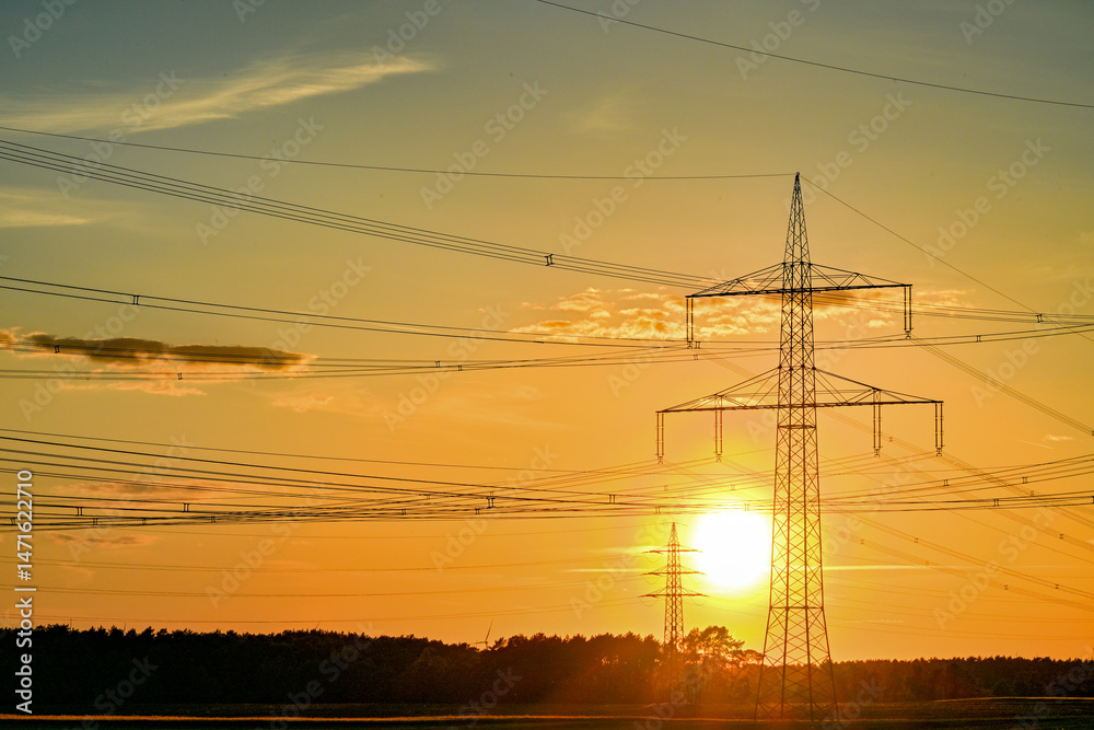Fototapeta premium Power poles in spring, sunset, in the field and on the meadow, Brandenburg, Germany