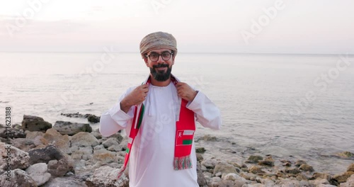 Front view of an Omani man with Oman scarf flag , wearing omani traditional dishdasha and Musaar