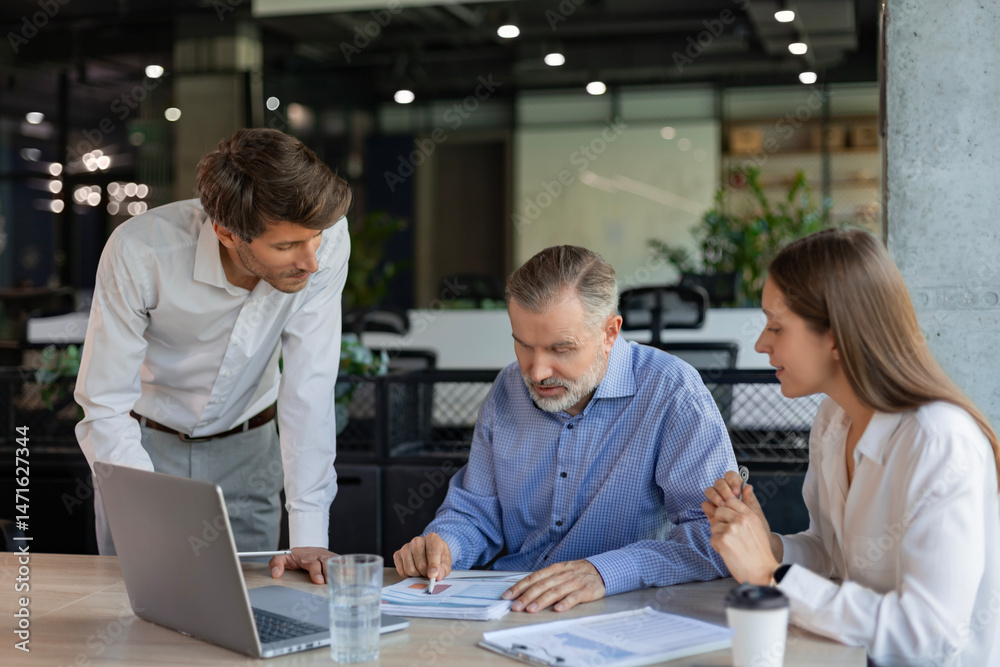 Fototapeta premium Successful businesspeople working in a coworking space working with laptop discussing strategy and business plan in modern office.
