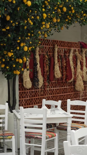 Cozy corner in a traditional Greek tavern in Athens with a white table, white chairs with colorful seats, set for guests, decorated in authentic Greek style, clean and empty, medium shot