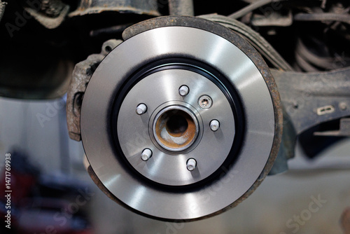 New Car Brake Disc Installed on Wheel Hub, Close up showing detailed automotive parts during car maintenance or repair.  
