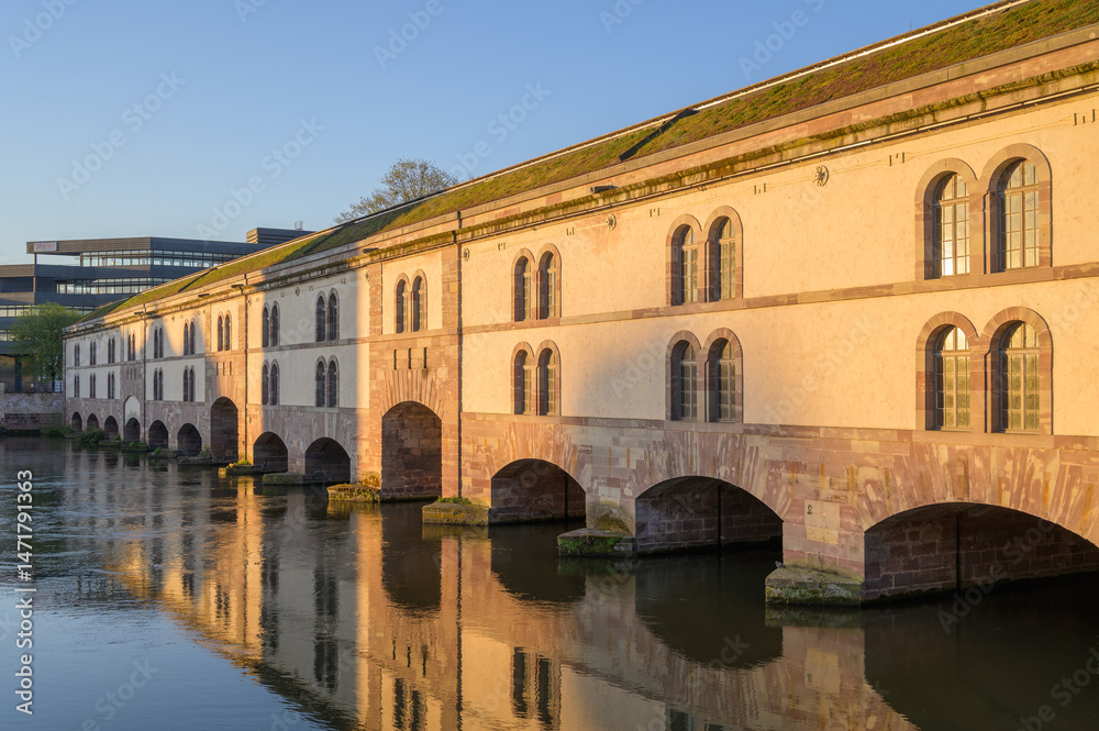 Obraz premium Historic sandstone bridge and weir in Strasbourg, France, showcasing sculptures and architectural beauty from the 17th century