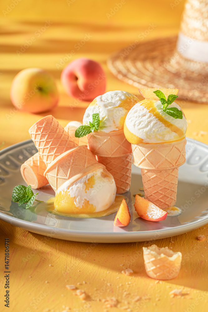 Sweet and homemade peach ice cream in a waffle cone.