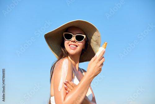Woman applying sunscreen creme on tanned shoulder. Skincare Concept.  Body Sun protection suncream. Gir applying moisturizing sunscreen lotion on back.