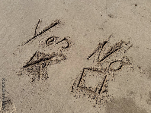 in a  sandy beach the words Yes No are written to tick