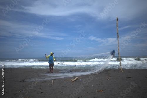 A fisherman prepares a net to catch fish at Congot Beach, Kulon Progo, Yogyakarta, Indonesia photo