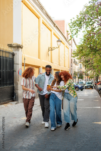 Multiethnic friends walking and using smartphone on city street