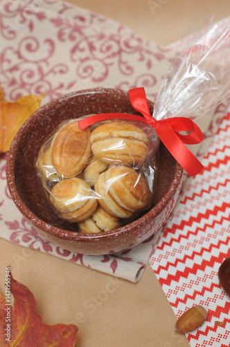cookies that look like nuts, tied with a bow in a brown ceramic pot. In the background are acorns, maple leaves and a napkin