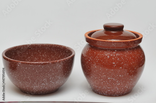 two brown ceramic pots one with a lid on a white background