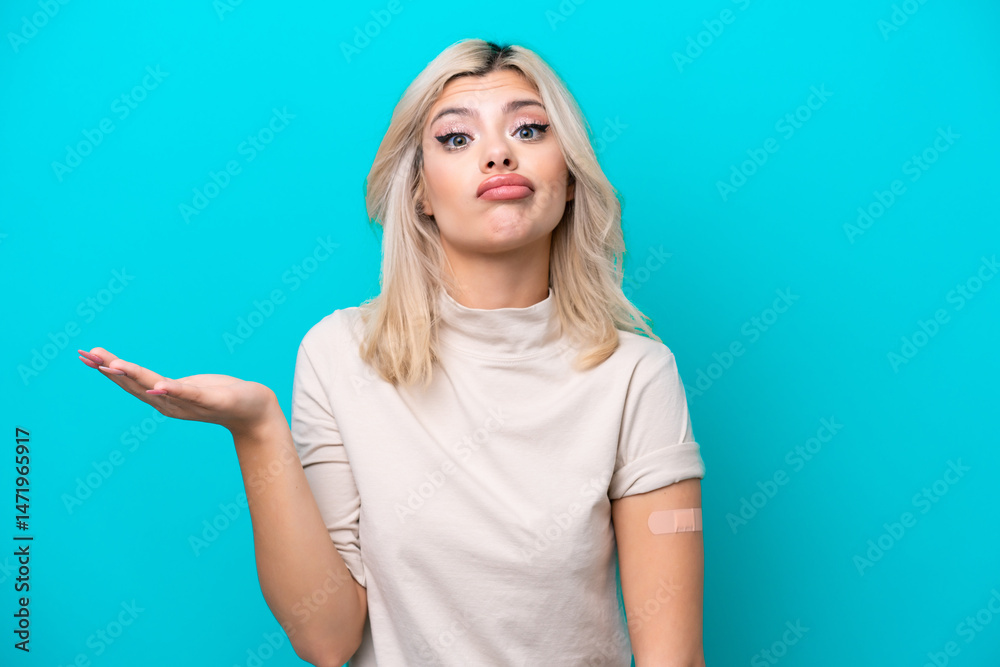 Fototapeta premium Young Russian woman wearing band aid isolated on blue background making doubts gesture while lifting the shoulders