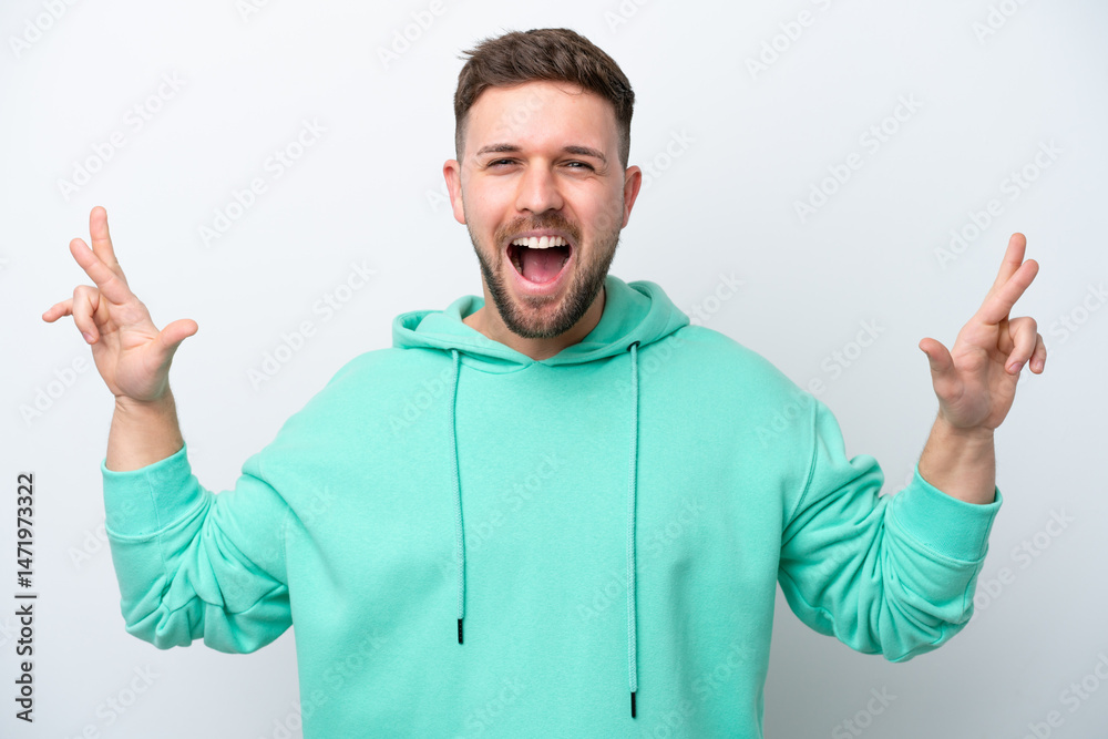 Fototapeta premium Young caucasian man isolated on white background with fingers crossing