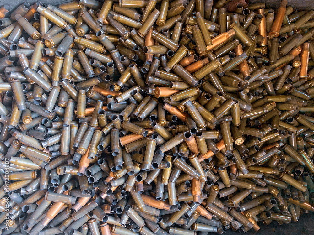 Naklejka premium Zużyte łuski po nabojach rozrzucone na ziemi strzelnicy