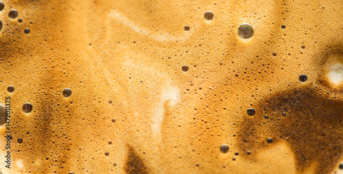 Coffee foam texture background, creamy coffee foam, rich, frothy surface, freshly brewed cup of hot latte. Espresso. Top view of cappuccino milk foam closeup. Creamy coffee macro shot