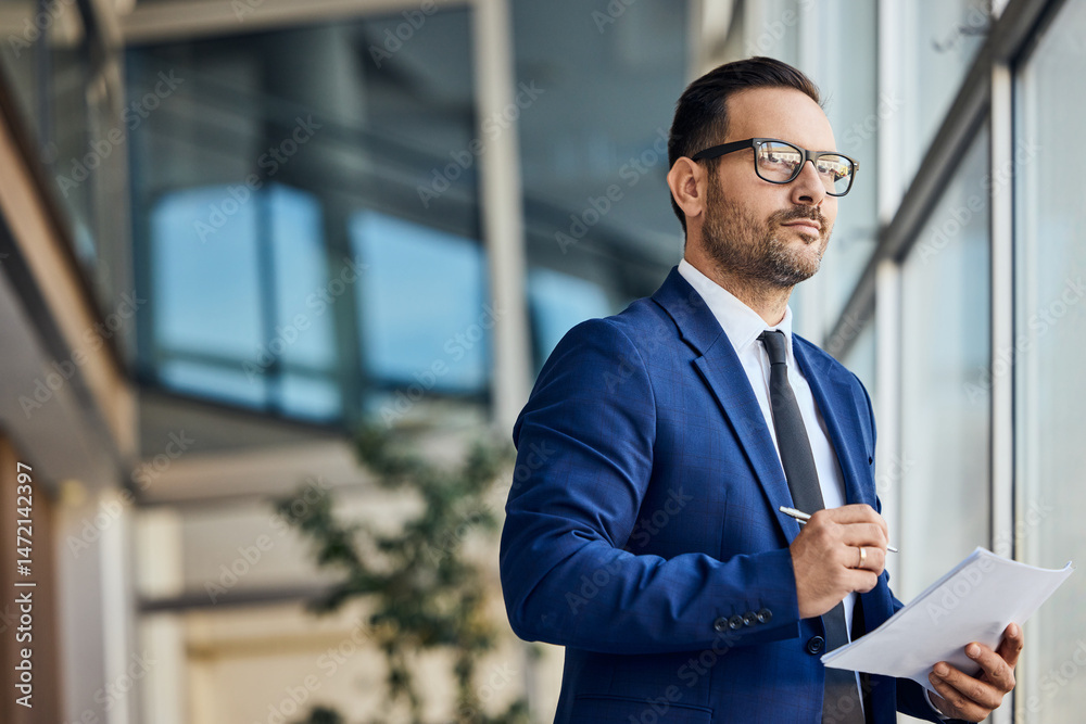 Fototapeta premium Confident Professional Man Standing in Modern Office With Documents and Pen