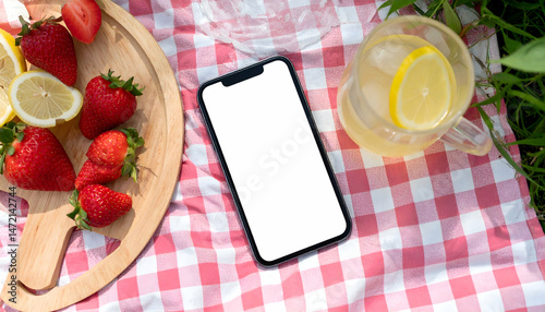Mobile phone on picnic blanket with fresh fruit and refreshing drink