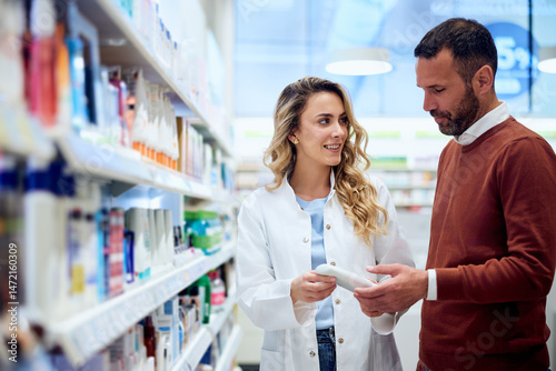 Fotografie Smiling Pharmacist Assisting Customer in a Well-Organized Pharmacy Environment