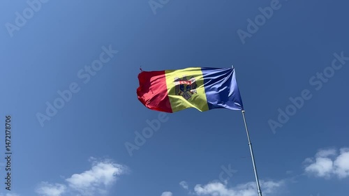 Flag of Republic of Moldova waving in the wind, on background of blue sky.