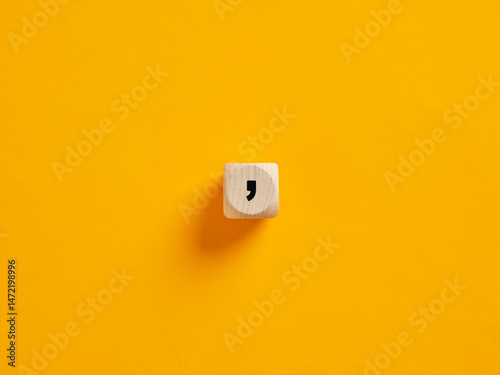 Photos Wooden cube showing comma sign on yellow background