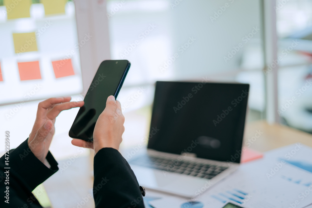 Fototapeta premium Asian businesswomen are confident in the modern workplace, using smartphones for communication and networking.