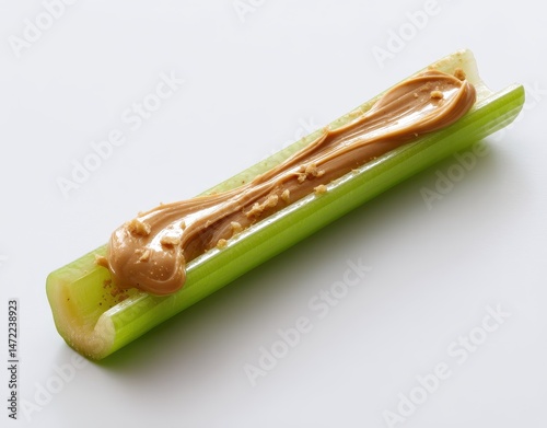 Fresh green celery stick topped with creamy peanut butter spread on a plain background for healthy snack presentation and culinary inspiration