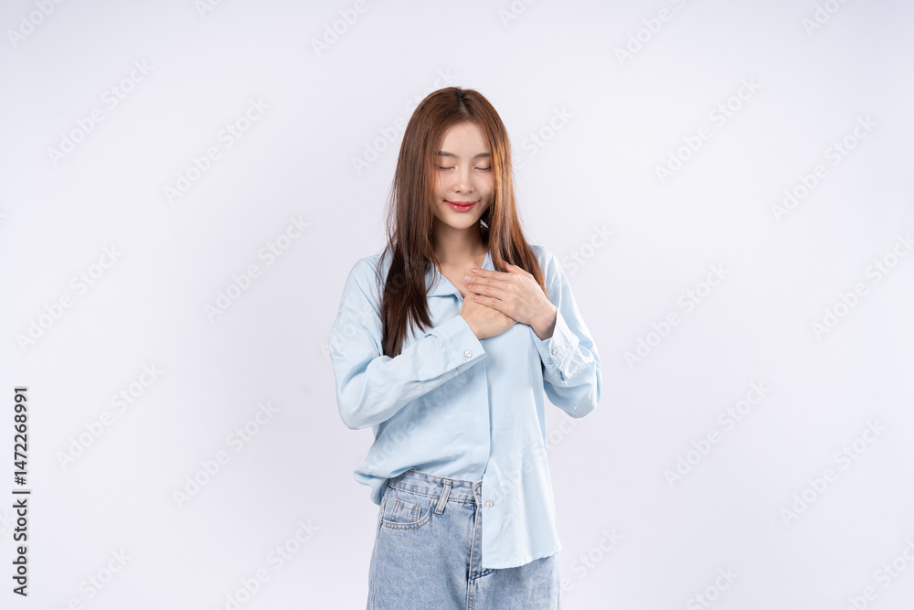 Woman showing gratitude gesture with both hands over her heart, happy smiling expression, portrait on white background Woman showing gratitude gesture with both hands over her heart, happy smiling expression, portrait on white background