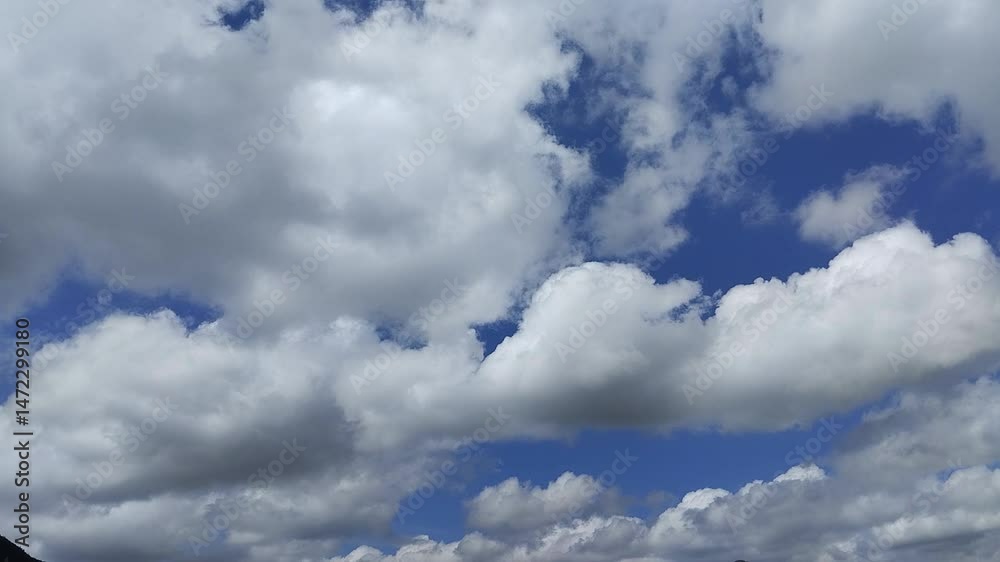 Un cielo de azul con varias nubes de color blanco y gris con un movimiento lento