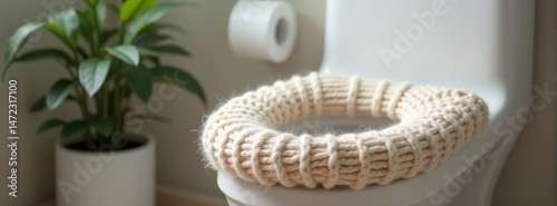 Cozy knit toilet seat cover in bright bathroom with potted plant in background.