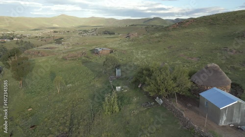 Fly from small rural farmstead, reveal Semonkong river flowing through green valley in Lesotho