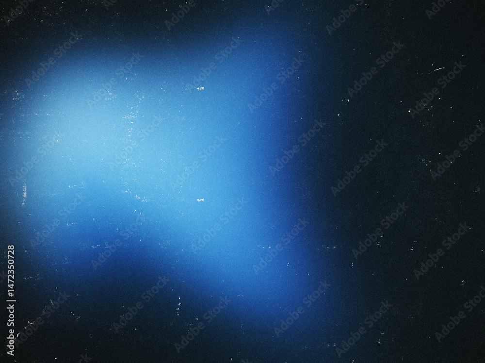 Fototapeta premium Blurred blue spot on a black background with dust, noise, and scratches. Perfect for use as an overlay texture or in various graphic design projects.