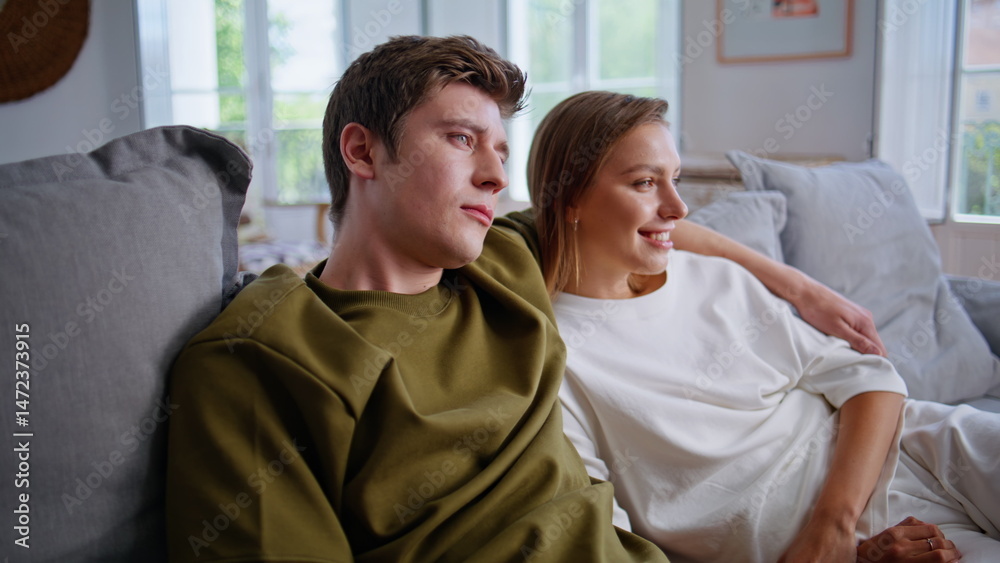 Happy lovers watching tv together on weekend. Teenager couple embracing on sofa