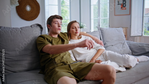 Obraz na płótnie Happy spouses enjoying tv program at couch. Smiling man embracing girlfriend w salonie