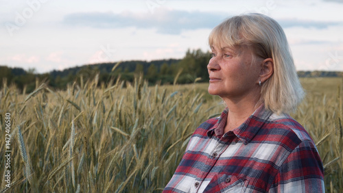 Portrait of a farmer's woman in a rural wheat field. He stands motionless and looks into the distance.