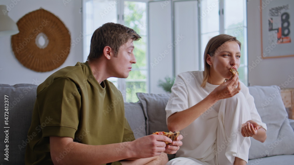 Hungry friends enjoying pizza watching TV at home sofa closeup. Happy people
