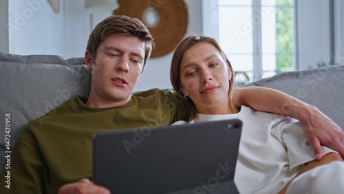 Relaxed teenagers looking tablet in house closeup. Couple spending time together